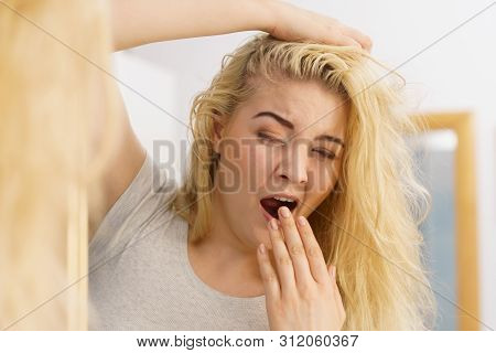 Young Blonde Female Feeling Dull And Tired After Waking Up. Woman Yawning Being Sleepy In Bathroom.