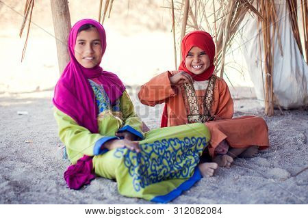 Egypt, Hurghada, 12 May 2019, Two Little Girls Sitting On The Ground In The Beduin Village