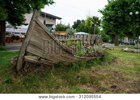 Old Wooden Boat As A Decoration (flowerbed With Flowers) On The Streets Of The Seaside Town. Pomorie