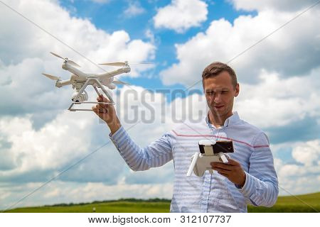 Young Man Controlling Drone In Field. Drone Operator Holding A Transmitter.