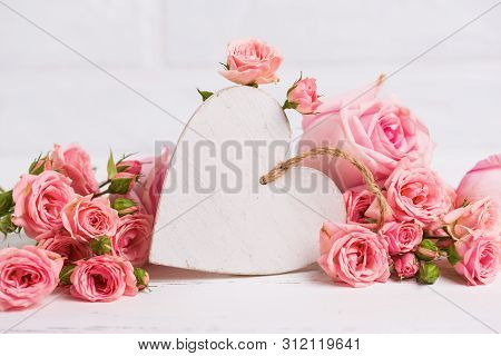 Decorative Rustic White  Heartt And Blush Roses Flowers  Against White Brick Wall. Selective Focus. 
