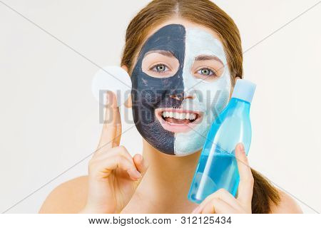 Woman With Clay Carbo Black Mask On One Half Face And White Mud On Second Half. Girl Removing Cosmet