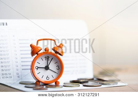 Alarm Clock On Coins Stack On On Bank Passbook Background. Retirement Planning. Money Saving And Inv
