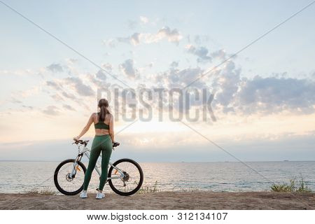 Portrait Of A Beautiful Young Brunette Woman Resting After Bicycle Ride At Sunrise. Model Listening 