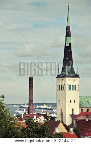Tower Oleviste In The Old City Of Tallinn Against The Sky And The Ferry In The Background. Side View