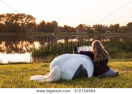 A Girl With A Horse By A Lake At Sunset