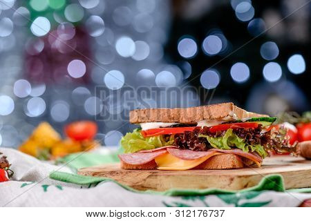 New Years Sandwich With Sausage, Tomatoes, Cheese, Sauce And Lettuce On A Wooden Board. Against The 