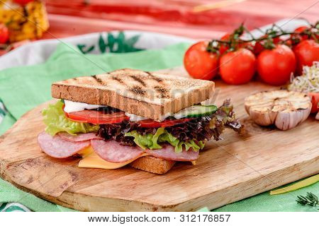 New Years Sandwich With Sausage, Tomatoes, Cheese, Sauce And Lettuce On A Wooden Board. Against The 