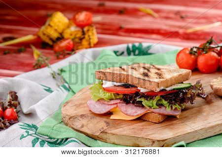 New Years Sandwich With Sausage, Tomatoes, Cheese, Sauce And Lettuce On A Wooden Board. Against The 