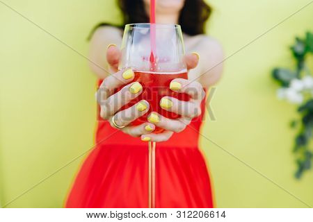 A Young Caucasian Woman Wearing Red Dress And Holding A Glass Of Lemonade With Two Hands