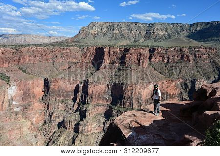 Young Woman Enjoys The Spectacular View From Toroweap Overlook In Grand Canyon National Park, Arizon