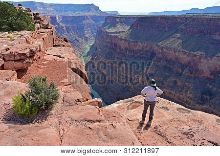 Young Woman Enjoys The Spectacular View From Toroweap Overlook In Grand Canyon National Park, Arizon