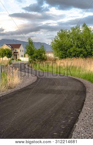 Paved Road With Yellow Traffic Delineator Posts Winding Through A Grassy Field