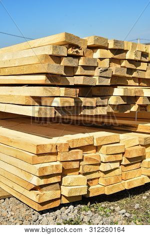 Stacked Lumber On Blue Sky.folded Wood.closeup Wooden Boards.the Surface Of The End Of The Board.lot