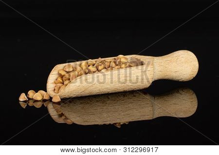 Lot Of Whole Raw Brown Buckwheat Grain With Wooden Scoop Isolated On Black Glass
