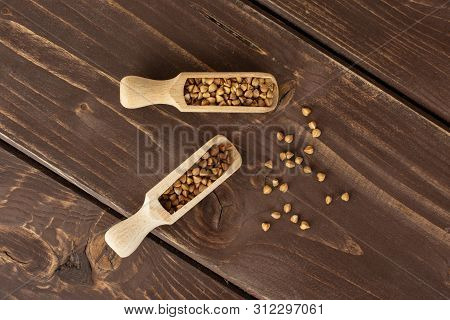 Lot Of Whole Hulled Raw Brown Buckwheat Grain With Wooden Scoop Flatlay On Brown Wood