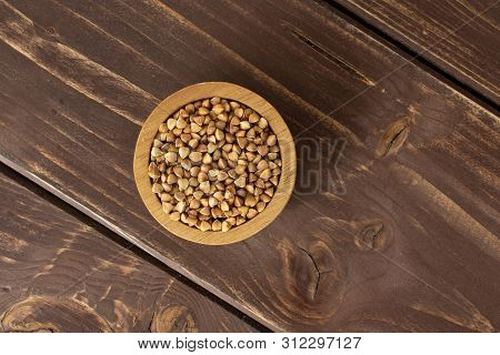 Lot Of Whole Raw Brown Buckwheat Grain In A Wooden Bowl Flatlay On Brown Wood