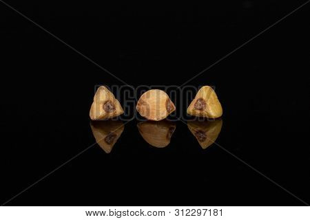 Group Of Three Whole Raw Brown Buckwheat Grain Isolated On Black Glass