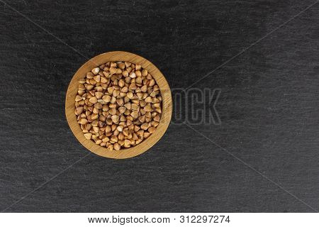Lot Of Whole Raw Brown Buckwheat Grain In A Wooden Bowl Flatlay On Grey Stone