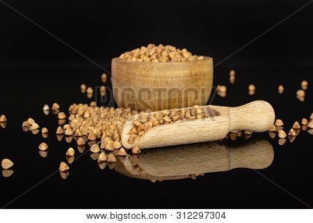 Lot Of Whole Hulled Raw Brown Buckwheat Grain In A Wooden Bowl With Wooden Scoop Isolated On Black G
