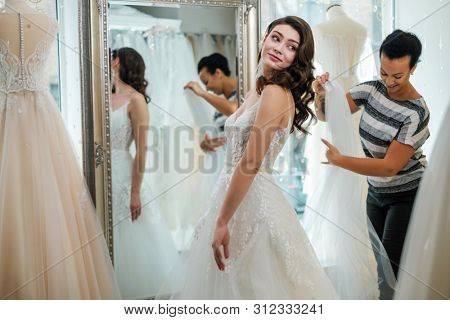 Beautifu bride choosing wedding dress in a wedding salon