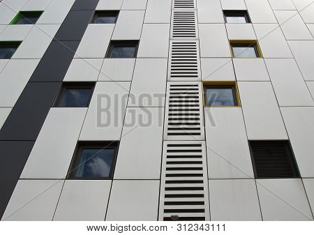 Close Up Of Silver Colored Metal Cladding Panels On A Modern Building With Repeating Windows And Geo