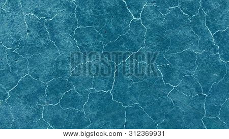 Beautiful Dark Blue Background. Light Cracks On The Surface. Texture Of Old Paint. Blue Soil Drought