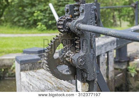 Closeup Detail Of Old Winding Gear Cog Wheel On Canal Lock Gate In Rural Setting