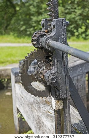 Closeup Detail Of Old Winding Gear Cog Wheel On Canal Lock Gate In Rural Setting