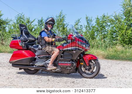 Eger, Hungary - July 04, 2019: Senior Motor Biker With Beard And Short Pants At Yellow Honda Goldwin