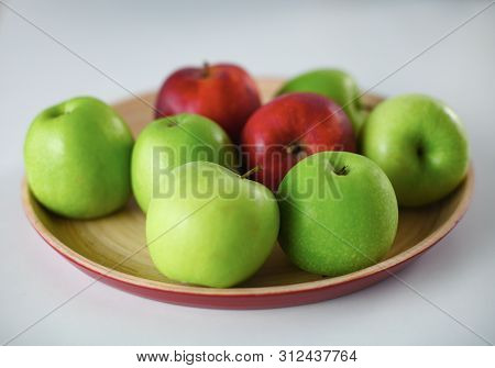Green And Red Apple Lies On A White Table