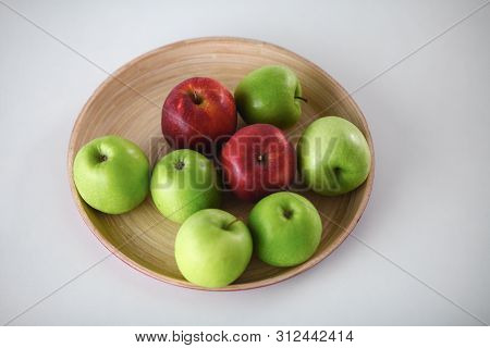 Green And Red Apple Lies On A White Table