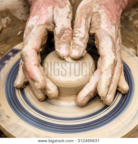 Potter’s Fingers Touch The Shapeless Piece Of Clay On The Rotating Wheel
