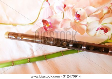 Two Traditional Chinese Bamboo Dizi Flutes Made From Wood With Tea Cups And Flowers In The Backgroun
