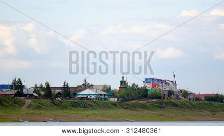 The Road From The Boats On The River Bank Leads To The Cliff With Houses And Silhouettes Of Cars Goi
