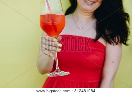 A Young Caucasian Woman In Red Dress Holding A Glass Of Cocktail And Smiling