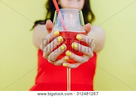 A Young Caucasian Woman Wearing Red Dress And Holding A Glass Of Lemonade With Two Hands