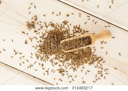 Lot Of Whole Small Dry Caraway Fruits With Wooden Scoop Flatlay On White Wood