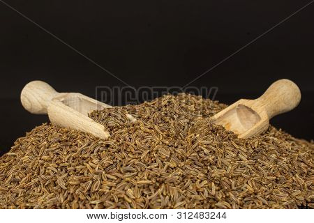 Lot Of Whole Dry Caraway Fruits With Two Wooden Scoops Closeup Isolated On Black Glass
