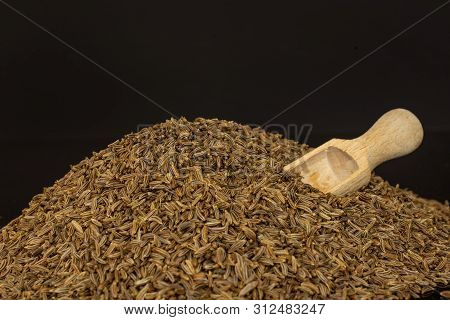 Lot Of Whole Dry Caraway Fruits Macro With Wooden Scoop Isolated On Black Glass