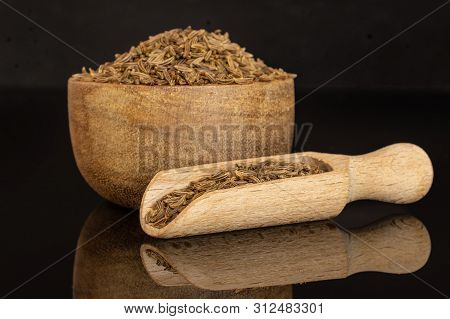 Lot Of Whole Dry Caraway Fruits In A Wooden Bowl With Wooden Scoop Isolated On Black Glass