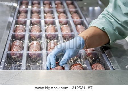 Workwoman Preparing Sausages In Red Casings For Storaging. Sausage Production Line. Sausage Producti