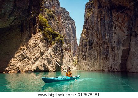 Woman on a kayak in the Pyrenees mountains in Catalonia on the waters of the Mont Rebei Gorge