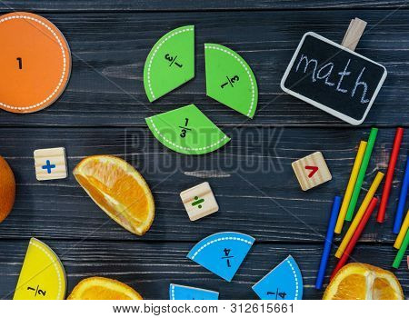 Сolorful Math Fractions And Oranges As A Sample On Dark Wooden Background Or Table. Interesting Crea