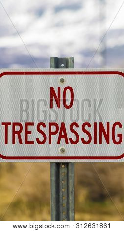 Vertical Tall Close Up Of White Sign Board With The Words No Trespasing Painted In Red Color