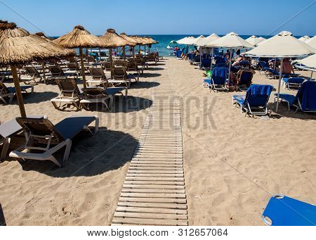 Malia, Crete, Greece - Juni 18, 2019: People Are Resting On A Sunny Day At The Beach In Malia, Crete
