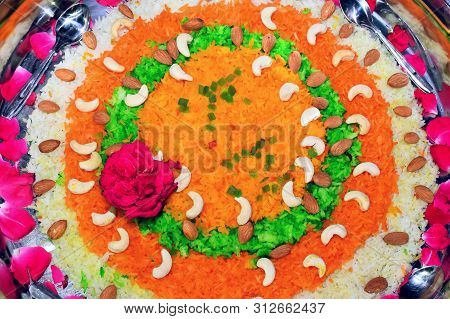 colorful boiled rice decorated with flowers and dry fruit_sweet casserole, in steel plate