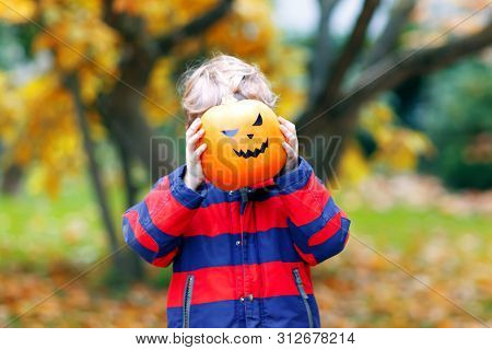 Happy Cute Little Kid Boy With Halloween Pumpkin Lantern. Funny Child In Colorful Clothes Having Fun
