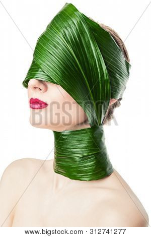 A close up portrait of a beautiful girl with a head rolled up in a leave posing in the studio over the white background. Beauty, nature, make up.
