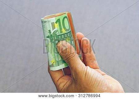 Hand Of Office Worker Man Gives A Bribe Roll Euro Banknote To An Employee In The Office. Concept - C